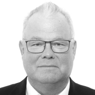 En man med kort ljust hår och glasögon ler mot kameran.