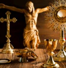 Religiösa föremål i guld framför en staty av en korsfäst figur.