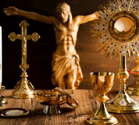 Religiösa föremål i guld framför en staty av en korsfäst figur.