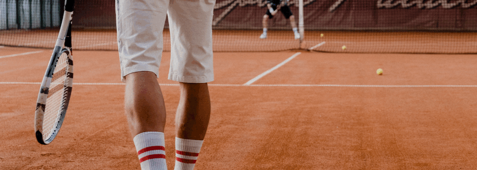 En tennisspelare går på en grusplan med ett racket i handen.